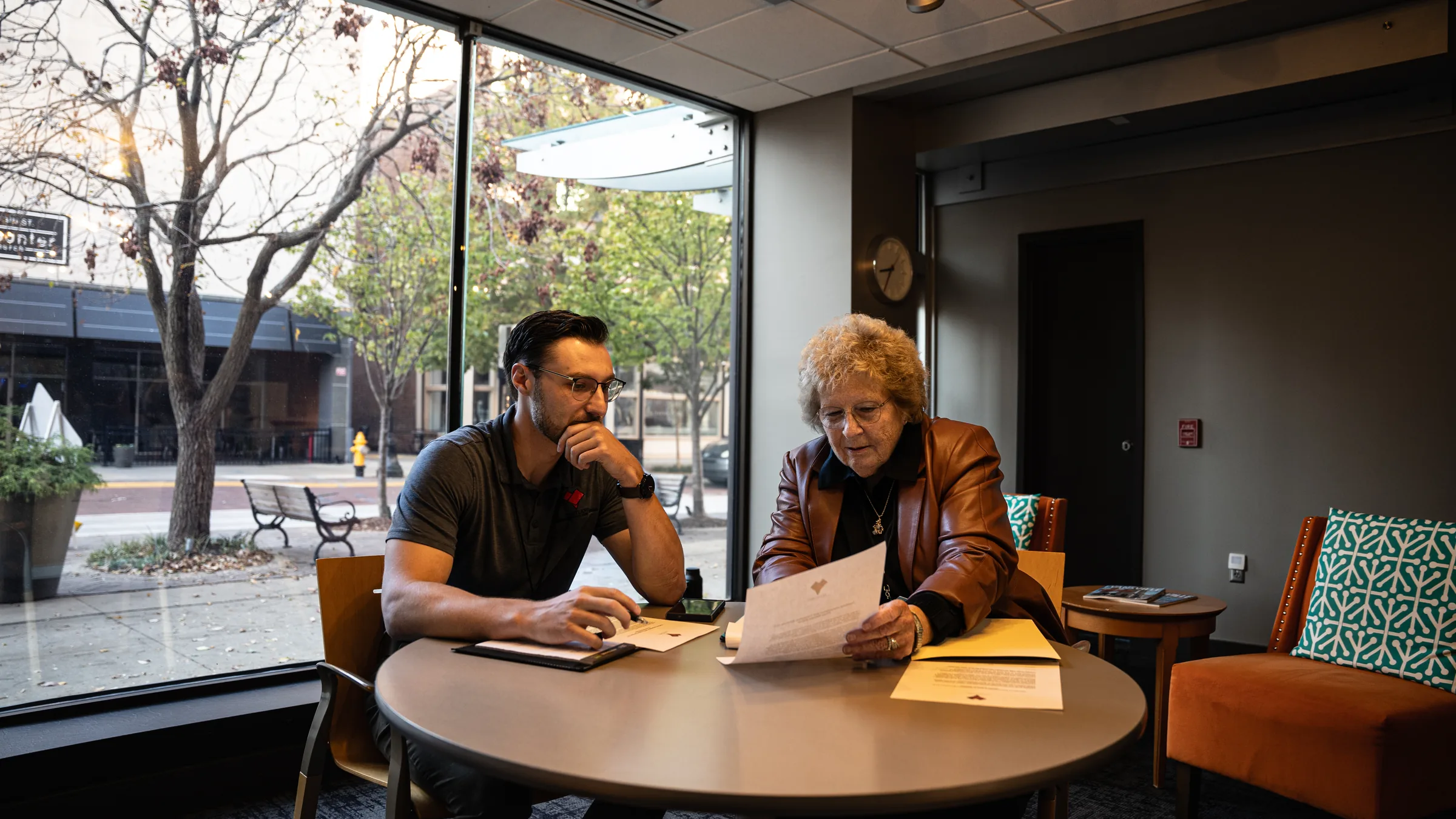 Two people reviewing printed documents at a conference table