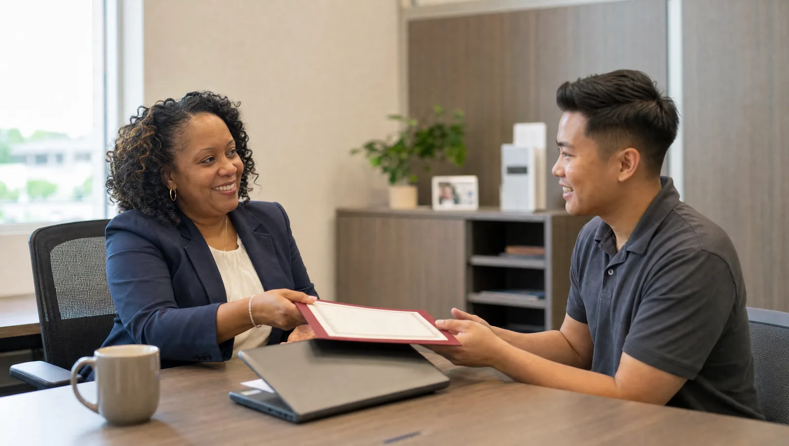 HR manager handing a new hire a certified language proficiency result in a folder across an office desk